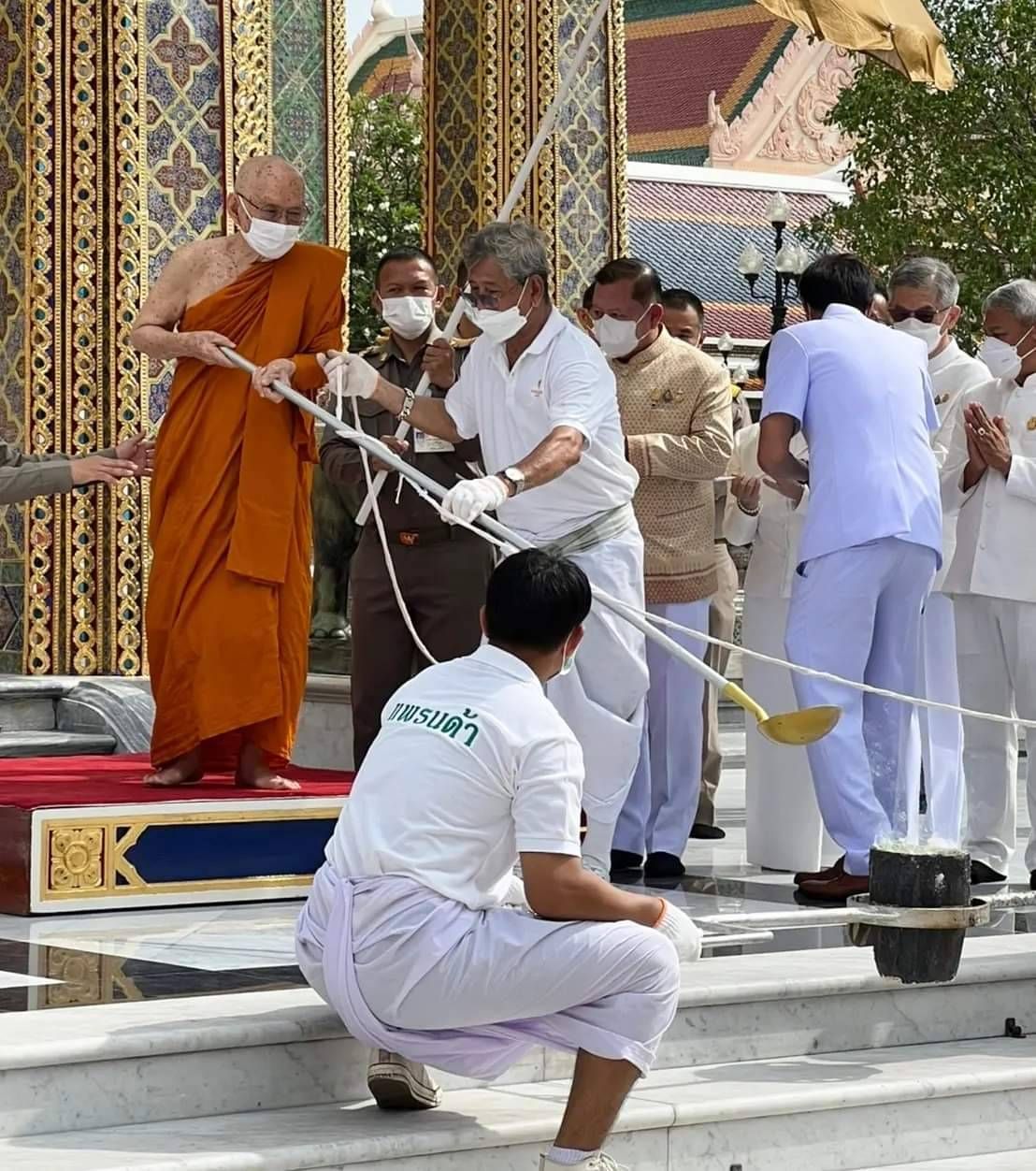 สมเด็จพระอริยวงศาคตญาณ สมเด็จพระสังฆราช สกลมหาสังฆปริณายก ทรงหย่อนแผ่นทองคำลงในช้อนเทลงในแบบ ทรงจับด้ายสายสิญจน์ประกอบพิธีเททอง 